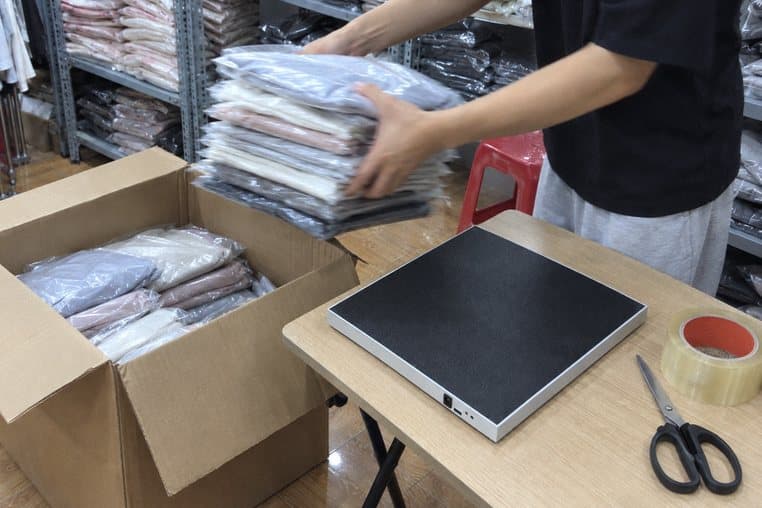 Hình minh hoạ: nhấc chồng áo đã soát trên đầu đọc RFID để bàn vào thùng chuyển sang cửa hàng khác
