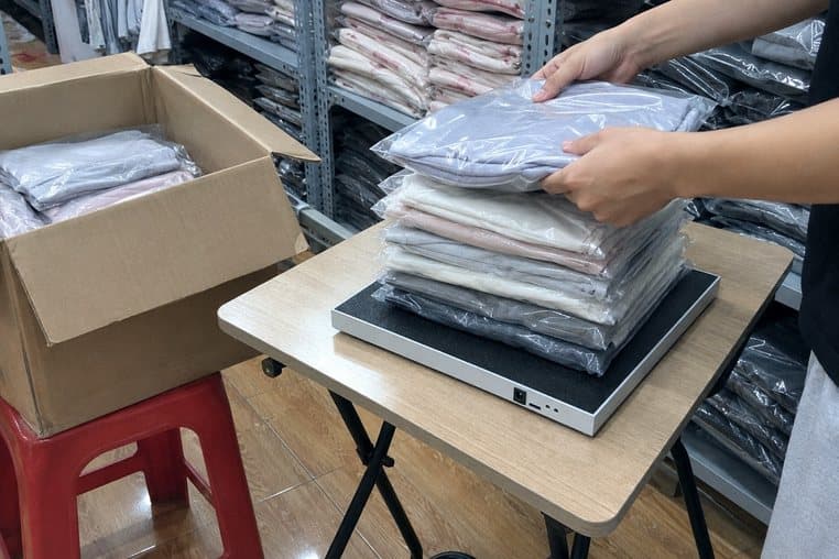 Hình minh hoạ: đặt chồng áo đóng túi mới về lên đầu đọc RFID để bàn