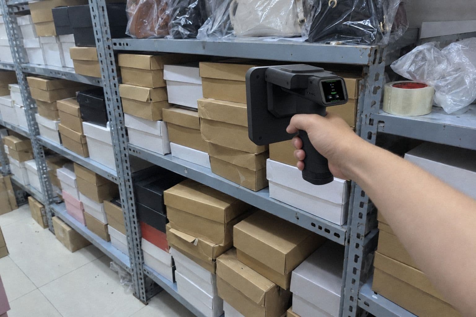 Hình minh hoạ: máy quét RFID cầm tay của Nextwaves rà dọc kệ sắt xếp hộp giày trong kho