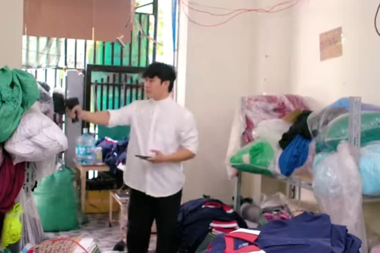 Kho hàng thời trang xếp đầy bao hàng, một người cầm máy đọc RFID rà qua các kệ