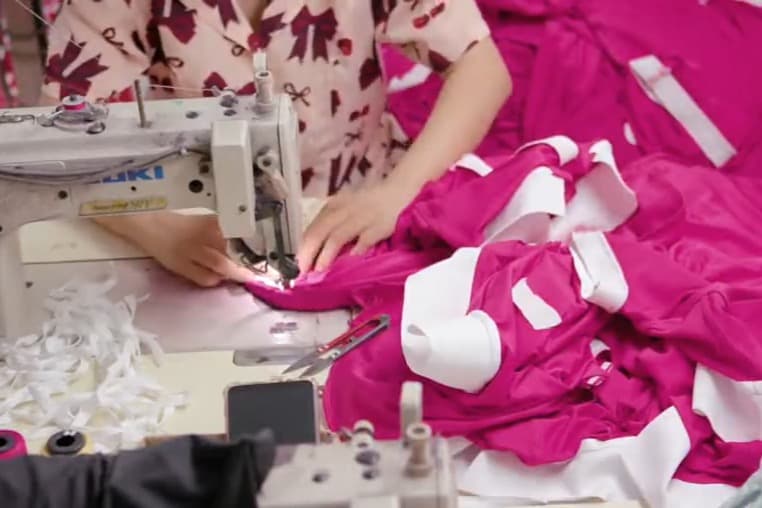 Công nhân may đang hoàn thiện một chiếc áo trên máy may công nghiệp trong xưởng